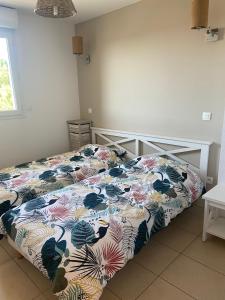 1 Schlafzimmer mit einem Bett mit Blumenbettdecke in der Unterkunft Villa dans résidence avec piscines proche plage in Belgodère