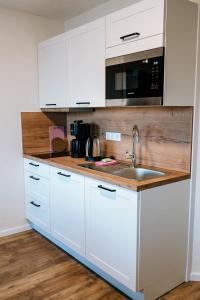 a white kitchen with a sink and a microwave at Dill Apartments Ilsede in Ilsede