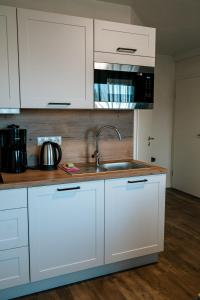 a kitchen with white cabinets and a sink at Dill Apartments Ilsede in Ilsede