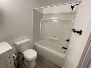 a white bathroom with a toilet and a bath tub at Home away from home in Winnipeg