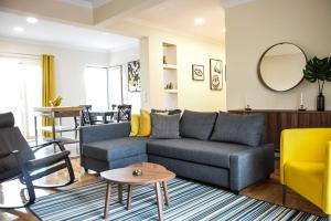 a living room with a blue couch and yellow chairs at The Parthenon Terrace ReNoVaTeD with a view ! in Athens