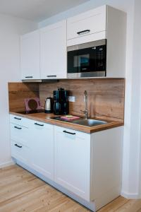 a kitchen with white cabinets and a sink at Dill Apartments Ilsede in Ilsede