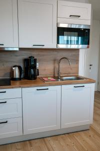a kitchen with white cabinets and a sink at Dill Apartments Ilsede in Ilsede