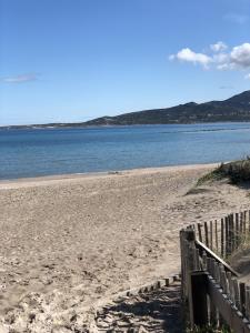 a sandy beach with a fence and the water at Studio Rez de jardin dans résidence privée près de la plage in Calvi