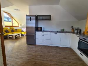 una cocina con nevera de acero inoxidable y armarios blancos en Apartments Katja en Kranjska Gora