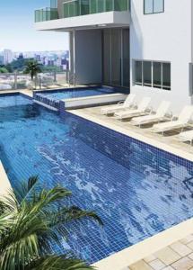 uma piscina com cadeiras e um edifício em Flat luxo, mobiliado c/ ar, wi-fi, pisc. e academia em Barueri