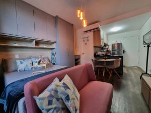 sala de estar con sofá rosa y cocina en Flat luxo, mobiliado c/ ar, wi-fi, pisc. e academia en Barueri