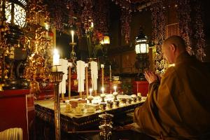 a man sitting in front of a table with candles at Koyasan Shukubo Saizenin in Koyasan