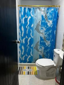 ein Bad mit einem WC und einem blauen Duschvorhang in der Unterkunft Villa Linda in Doradal