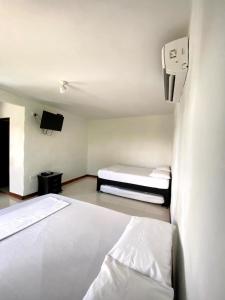 Kleines Zimmer mit 2 Betten und einem TV in der Unterkunft Villa Linda in Doradal