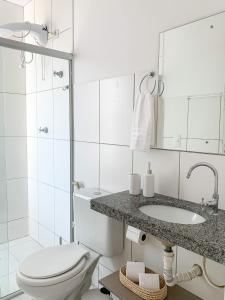 a white bathroom with a toilet and a sink at Casa Iva - Condomínio Fechado in Marechal Deodoro