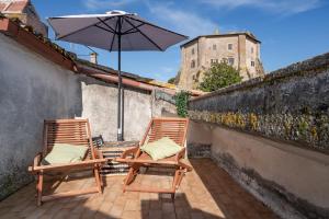 two chairs sitting on a patio with an umbrella at Casa Lago e Camino in Capodimonte