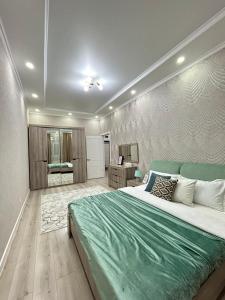 a bedroom with a large bed with a green blanket at Apartments GREEN PLAZA с видом на море in Aktau
