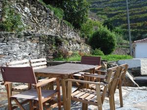 a wooden table with two chairs and a stone wall at Country house Quinta da Salgueira in Alijó