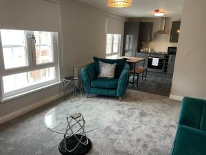 a living room with a green chair and a glass table at Cosy two bedroom apartment in Bishop Auckland