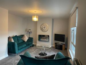 a living room with a green couch and a tv at Cosy two bedroom apartment in Bishop Auckland