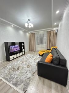 a living room with a couch and a flat screen tv at Apartments GREEN PLAZA с видом на море in Aktau