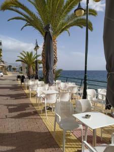 a group of tables and chairs and the ocean at Doll house next to the sea in Agioi Theodoroi