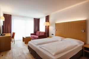 una habitación de hotel con una cama grande y una silla en Hotel Melodia del Bosco en Badia