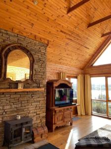 a living room with a stone fireplace and a tv at Fern Lodge. Drumcoura Lake Resort, in Ballinamore