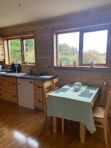 a kitchen with a table and a sink and windows at Fern Lodge. Drumcoura Lake Resort, in Ballinamore