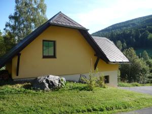 a yellow house with a rock in front of it at Chata Danuše in Ludvíkov