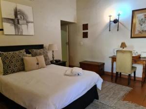 a bedroom with a large white bed and a desk at Khaya Africa Guesthouse in Midrand