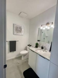 La salle de bains blanche est pourvue de toilettes et d'un lavabo. dans l'établissement Black Mountain Amazing Home on Golf Course, à Kelowna