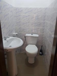 La salle de bains est pourvue de toilettes blanches et d'un lavabo. dans l'établissement Bel appartement au centre ville de calavi BENIN, à Abomey-Calavi