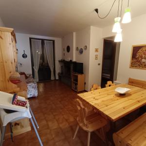 een woonkamer met een houten tafel en stoelen bij Appartamento incantevole a Sestola in Sestola