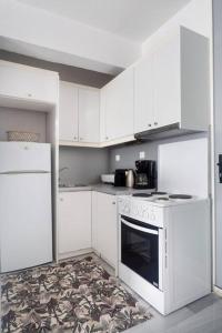 uma cozinha com armários brancos e um forno de fogão branco em Psyris Marble Loft ! em Atenas