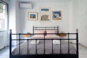 Schlafzimmer mit einem schwarzen Bett und rosa Kissen in der Unterkunft Psyris Marble Loft ! in Athen