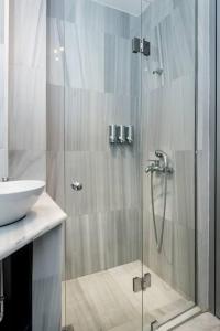 a shower with a glass door next to a sink at Psyris Marble Loft ! in Athens