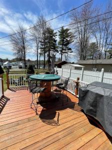 a patio with a table and chairs on a wooden deck at SUNNY BREAK- LIMIT 6 cottage in Raymond