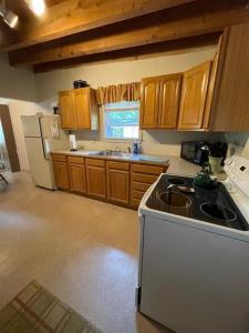 eine Küche mit Holzschränken und einem weißen Kühlschrank in der Unterkunft BASS COVE 1 LIMIT 6 home in Casco