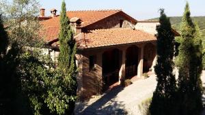 uma casa com telhado de azulejo e algumas árvores em Cas'al Verde em Fonterutoli