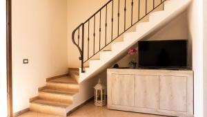 a living room with a tv on a dresser under a staircase at Appartamento sette posti vicino al centro di San Teodoro in San Teodoro