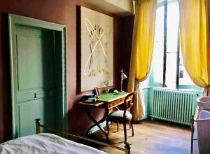 a bedroom with a desk and a bed and a window at Art-Maison in Le Dorat
