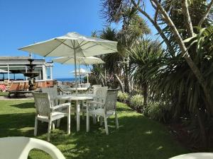 a group of tables and chairs with an umbrella at Livermead House Hotel in Torquay