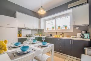 a kitchen with white cabinets and a table and chairs at Glyfada's Central Apartment in Athens