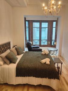 um quarto com uma cama grande e um lustre em LAS LETRONAS em Gijón