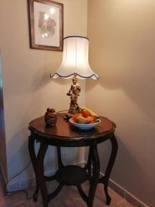 a table with a lamp and a bowl of fruit on it at Lovely Stone Village cottage in Snowdonia in Waenfawr