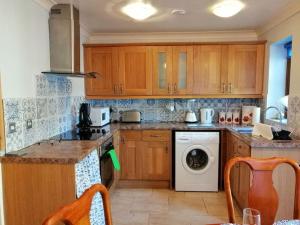 a kitchen with wooden cabinets and a washer and dryer at Lovely Stone Village cottage in Snowdonia in Waenfawr