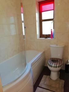 a bathroom with a toilet and a tub and a window at Lovely Stone Village cottage in Snowdonia in Waenfawr