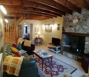 a living room with a couch and a stone fireplace at Lovely Stone Village cottage in Snowdonia in Waenfawr