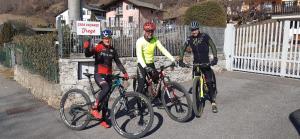 Três homens estão de pé com as suas bicicletas numa rua. em Casa vacanze Fregè em Castione Andevenno