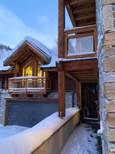 een houten huis met sneeuw op de veranda bij Châlets AOKI in Valloire