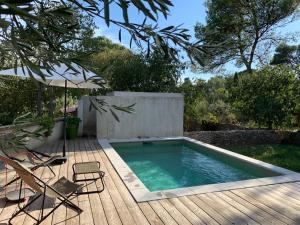 basen na drewnianym tarasie z 2 krzesłami i parasolem w obiekcie Loumaset-agréable petite maison-garrigues de Nîmes w mieście Nîmes