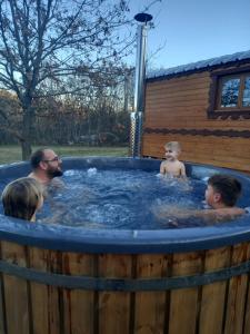 a man and two children in a hot tub at L'encantada- Roulotte in Rieux