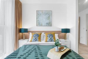 a bedroom with a green bed with two blue lamps at Birmingham City Centre Luxury Apartment in Birmingham